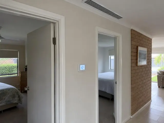 Ceiling air grille and wall controller in a home hallway with bedrooms and brick feature wall in Burleigh Waters