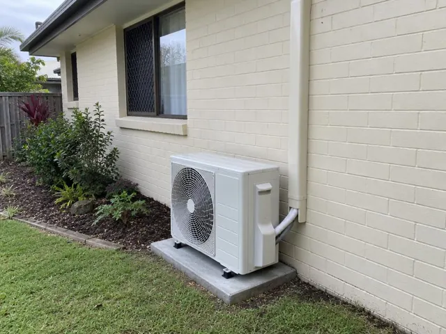 Outdoor air conditioner condenser on a concrete pad beside a cream brick house in Reedy Creek